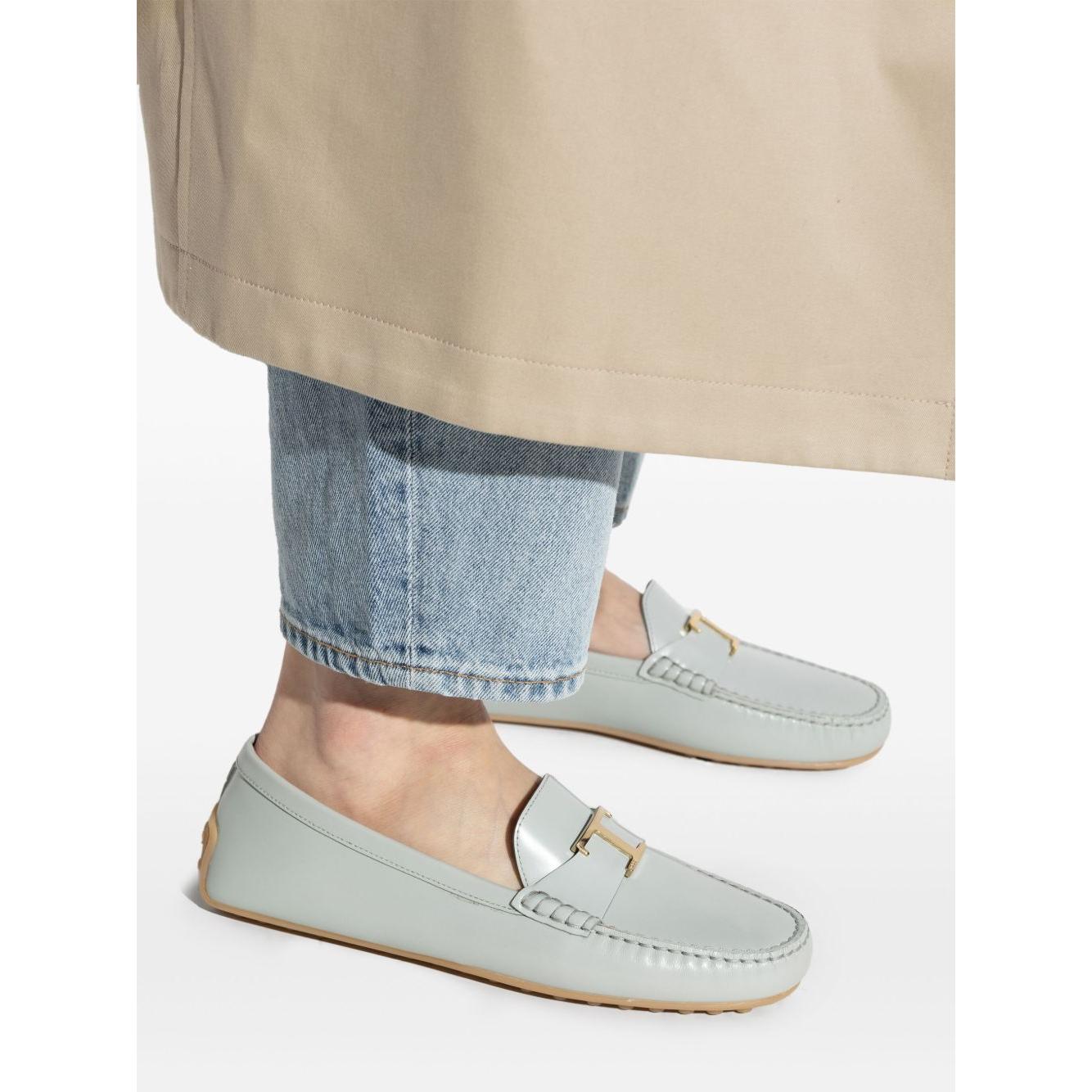 Light blue Tod's leather loafers with gold-tone hardware and flat sole, styled with denim jeans.