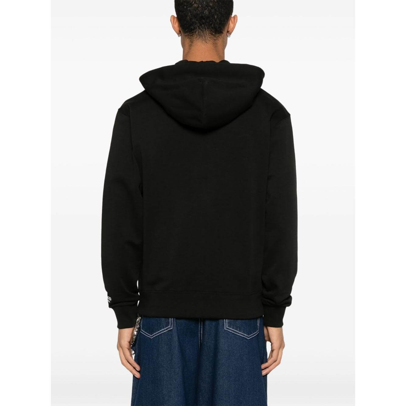 Back view of a Kenzo black cotton hoodie with signature Boke Flower motif, ribbed cuffs, and hem, worn by a model in blue jeans.
