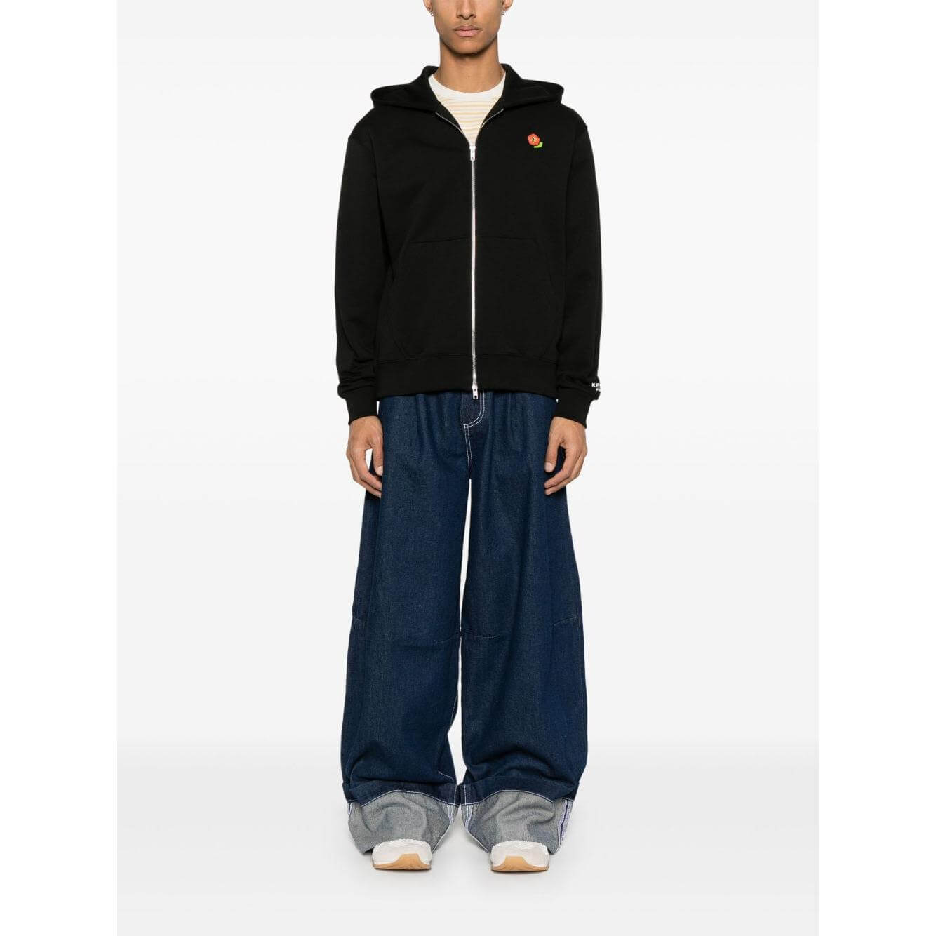 Model wearing Kenzo Black Sweater with Boke Flower motif, two-way zip, ribbed cuffs, and pouch pockets, showcasing casual style.