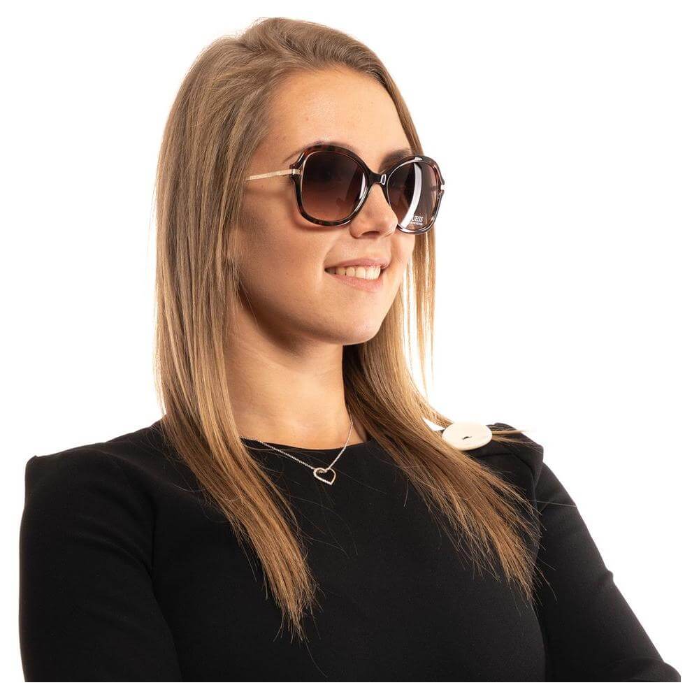 Woman wearing Guess Brown Butterfly Sunglasses with gradient lenses, showcasing stylish fashion accessory and full UV protection.