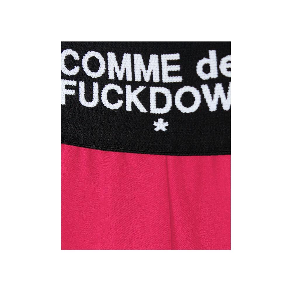 Close-up of Comme Des Fuckdown fuchsia polyester pants with logoed elastic waistband.