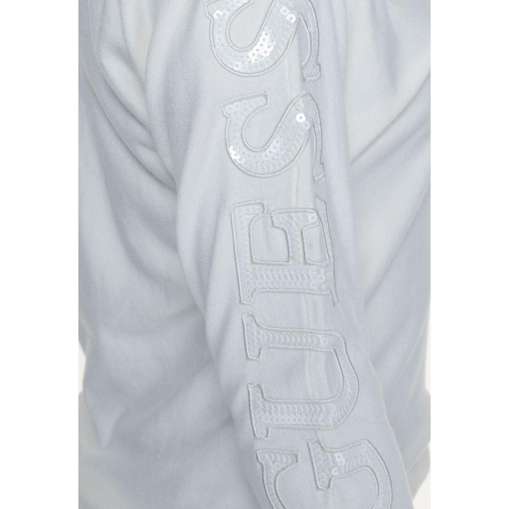 Close-up of sleeve detail on a Guess white viscose top, featuring embroidered branding with sequin accents, part of the Fall/Winter collection.