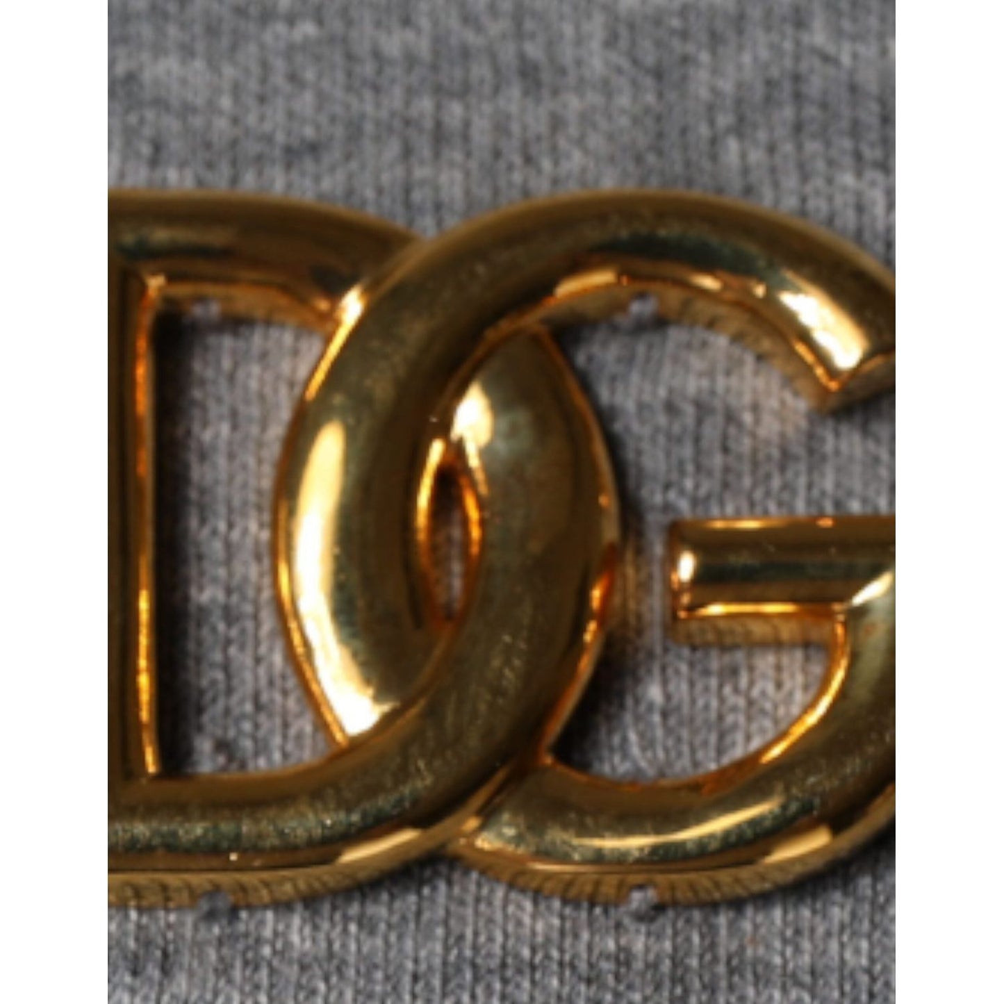 Close-up of Dolce & Gabbana gold logo embellishment on gray cotton-blend t-shirt fabric.