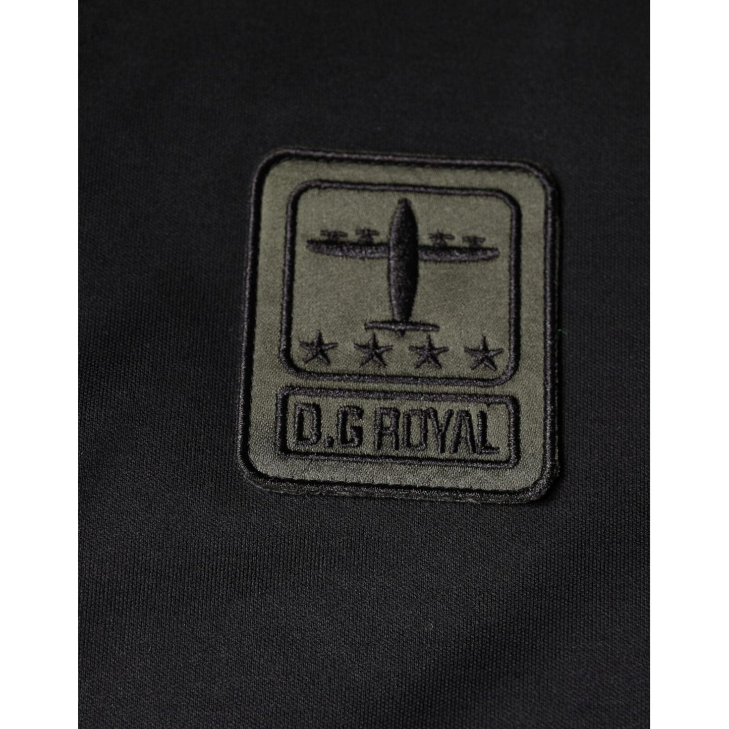 Dolce & Gabbana camouflage patch detail on black t-shirt, featuring D.G Royal logo design with airplane and stars. Fashion detail.