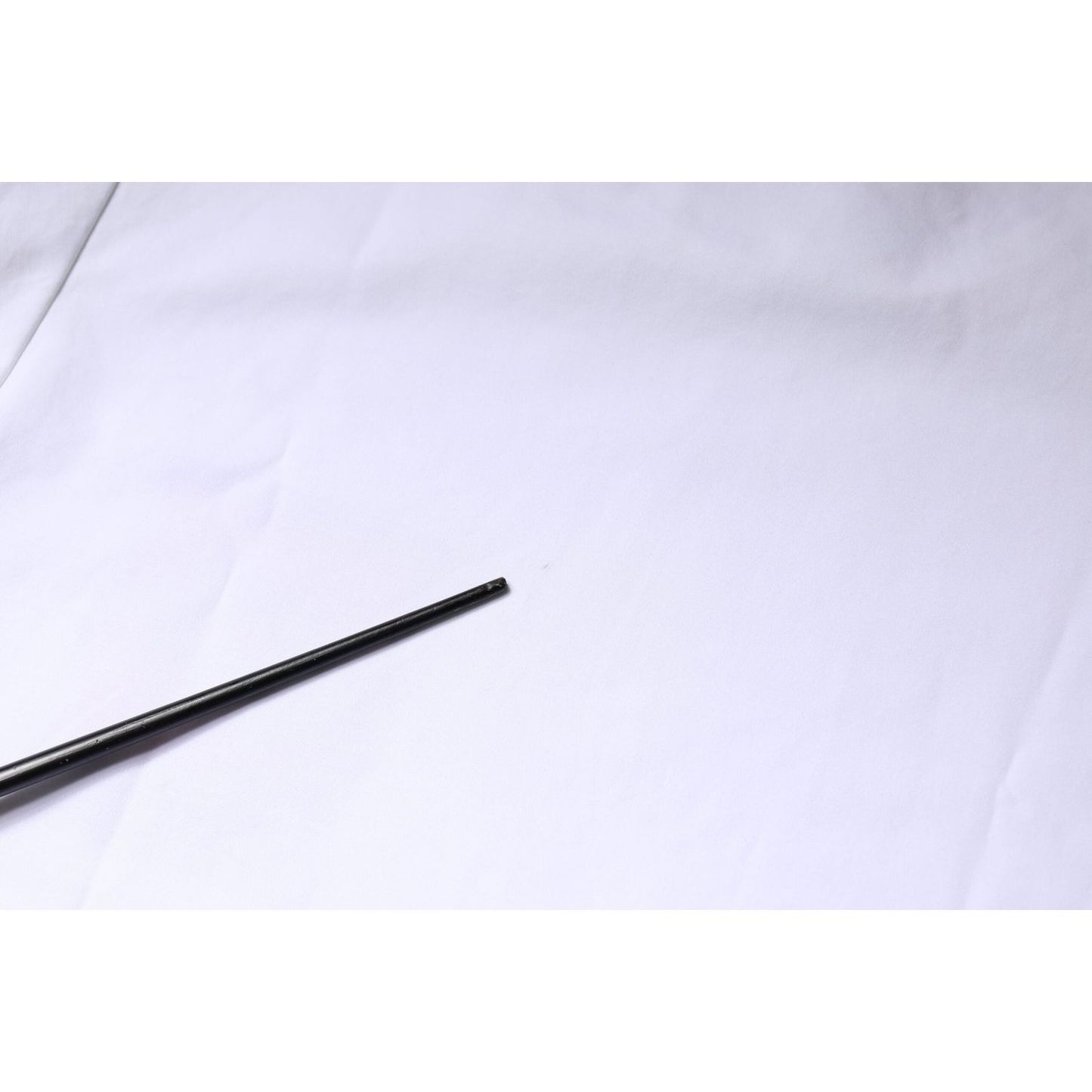 White fabric with a metal rod placed diagonally; clean surface with subtle texture. Ideal for backgrounds or creative projects.