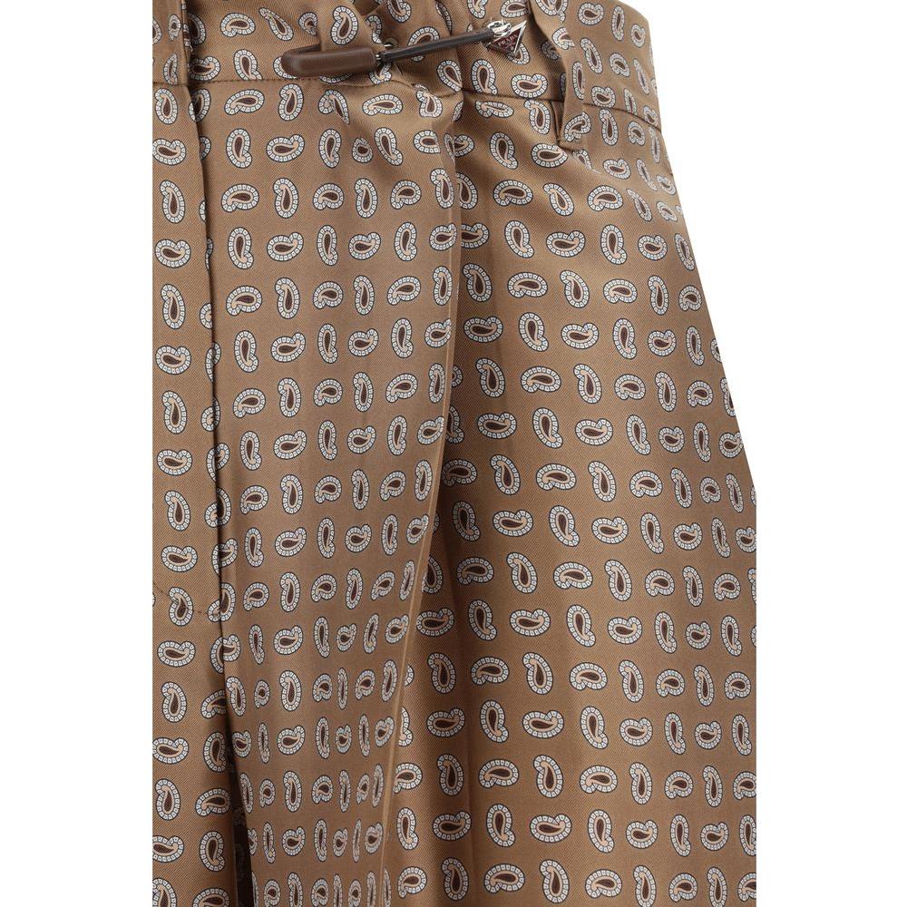 Prada silk pants with paisley pattern, featuring zipper closure, side slash pockets, welt back pockets, and waistband loops.