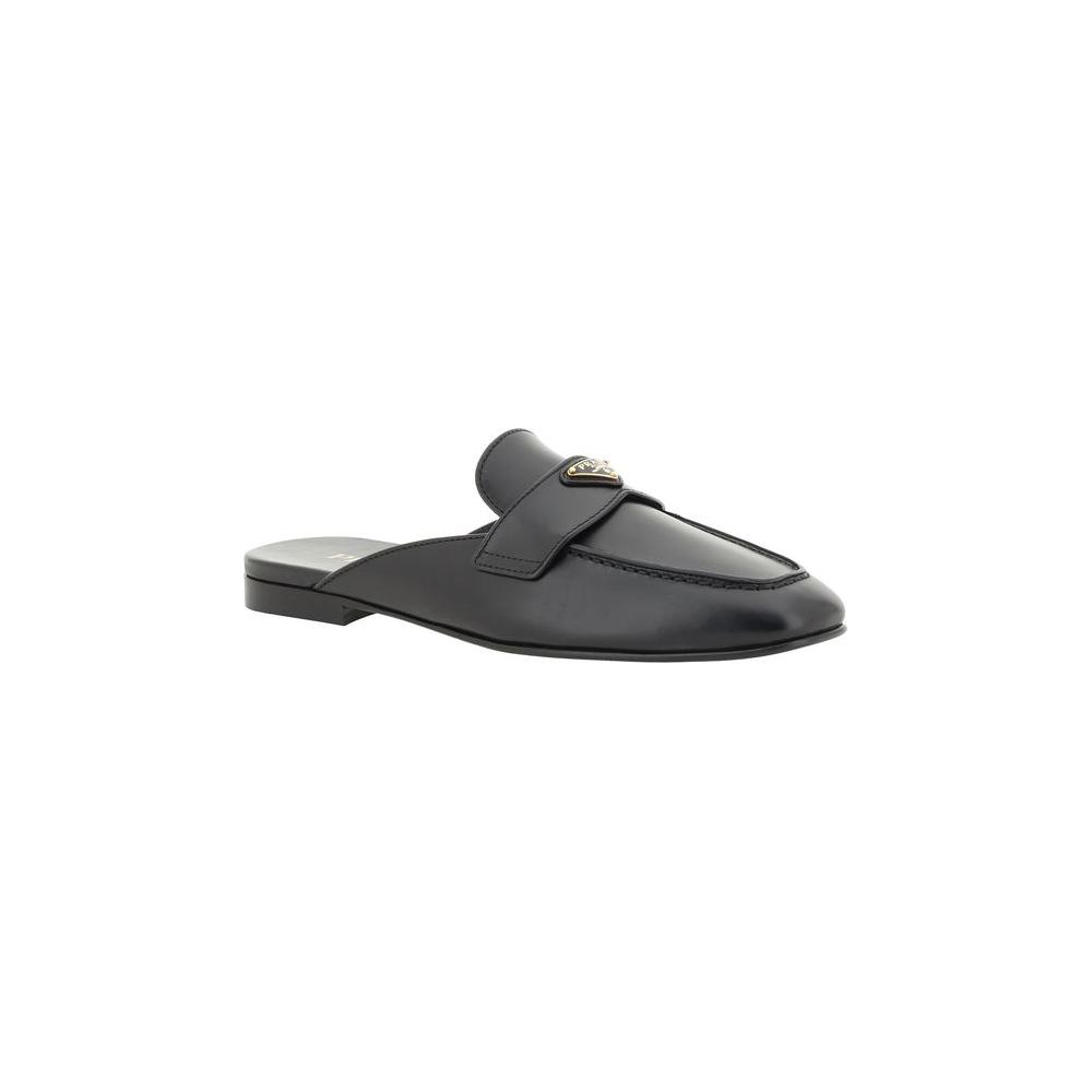 Black leather Prada mules with round toe, triangular plaque, flat sole, and logo insole.