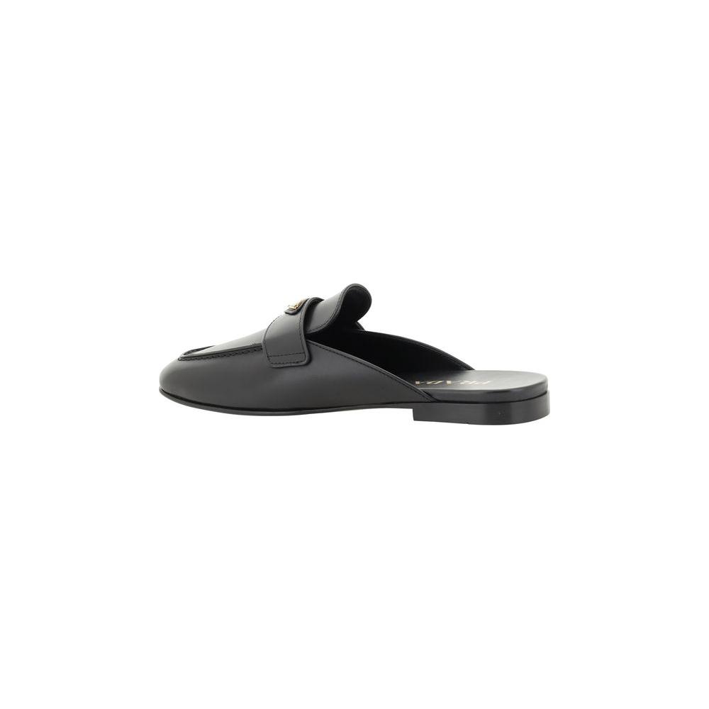 Black leather Prada mules with round toe and iconic triangular plaque, featuring a flat sole and contrasting logo insole.