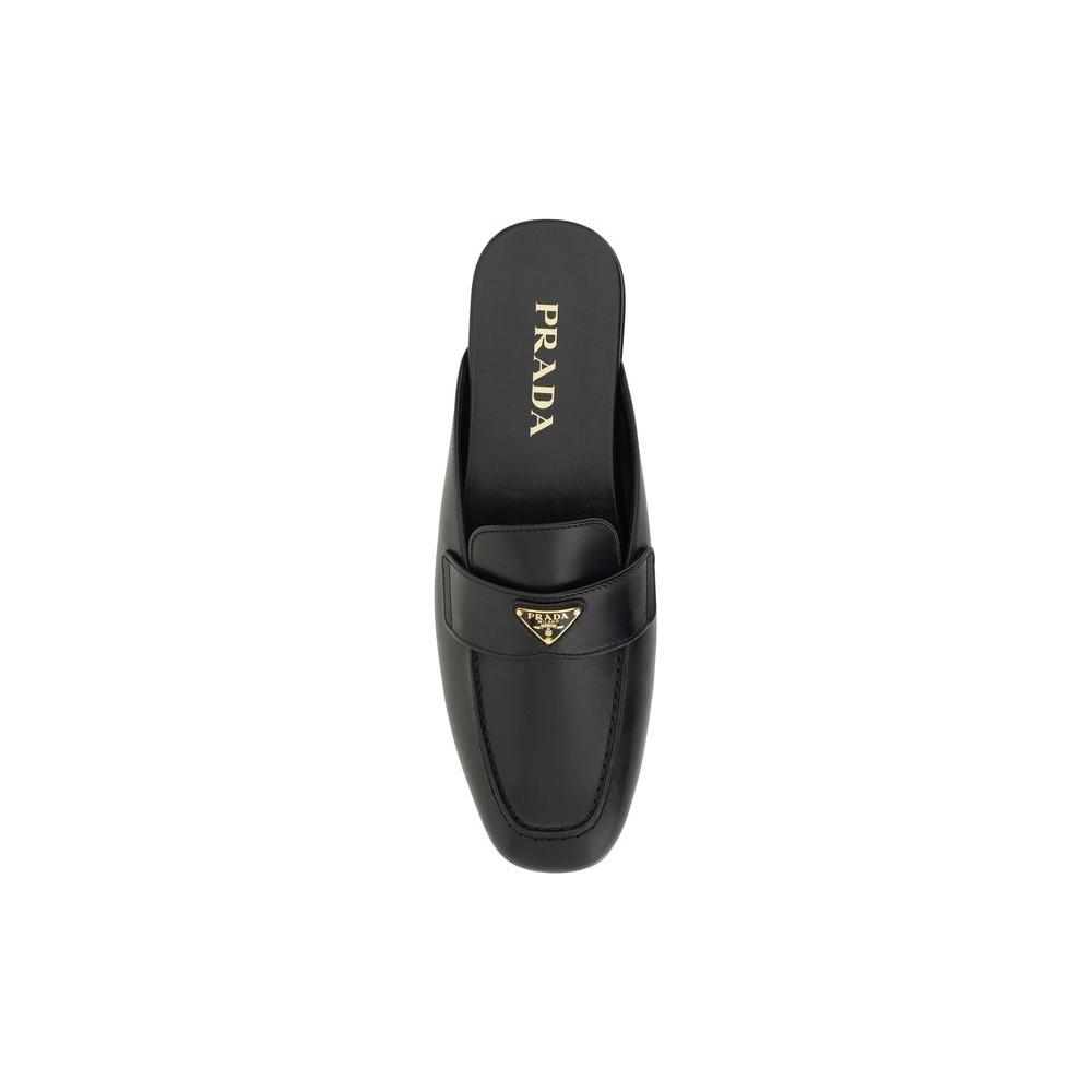 Prada leather mules with round toe, triangular plaque, flat sole, and contrasting logo insole