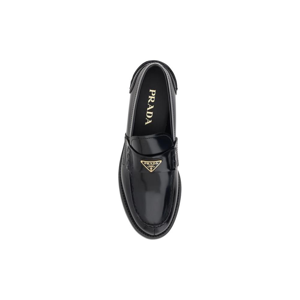 Prada leather loafers with enameled triangular logo plaque, round toe, and logo-embossed insole for elegant and versatile style.