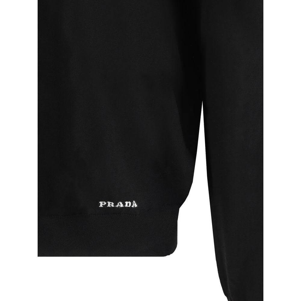Close-up of Prada recycled silk sweater with monogram, showcasing ribbed hem and minimalist design.