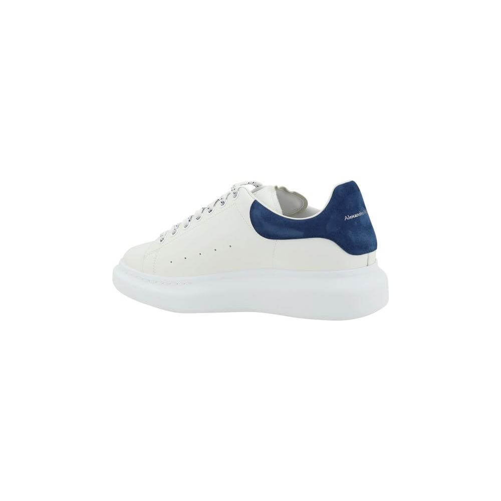 White Alexander McQueen leather sneaker with blue suede heel accent and embossed logos, side view.