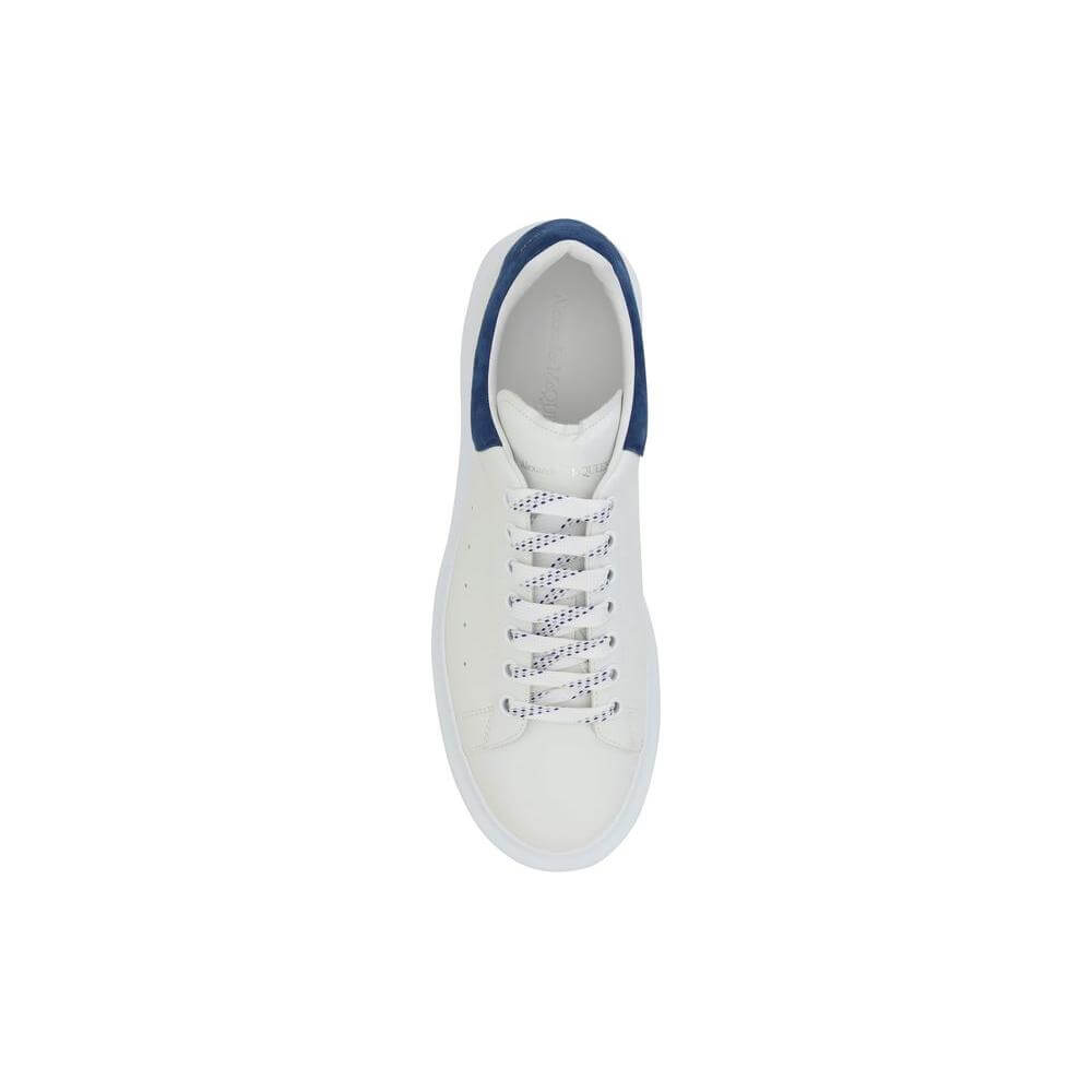 Top view of white Alexander McQueen leather sneakers with blue heel detail, featuring lace-up design and embossed logo accents.