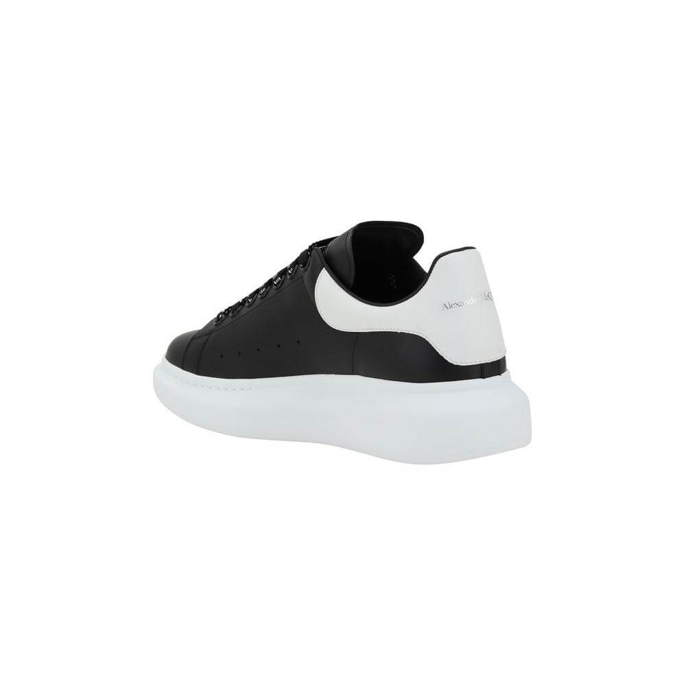 Side view of Alexander McQueen black and white leather sneaker with platform sole and logoed heel label.