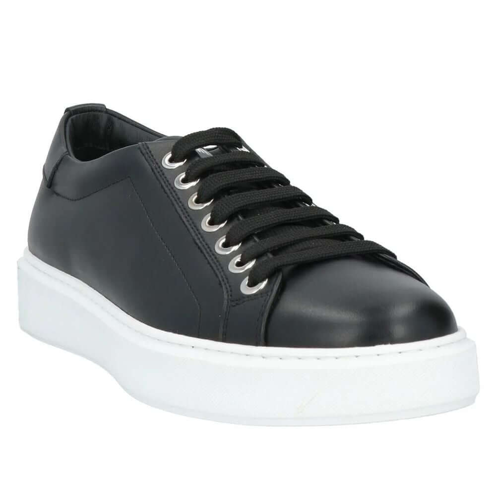 Les Hommes black calfskin men's sneaker with white sole, silver logo tongue, and metal heel ring on display.