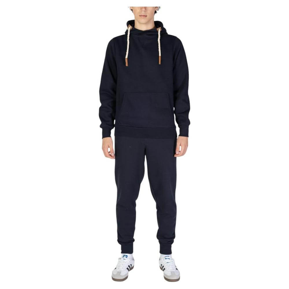 Man wearing a black hoodie with drawstrings and matching sweatpants, paired with white sneakers, against a white background.