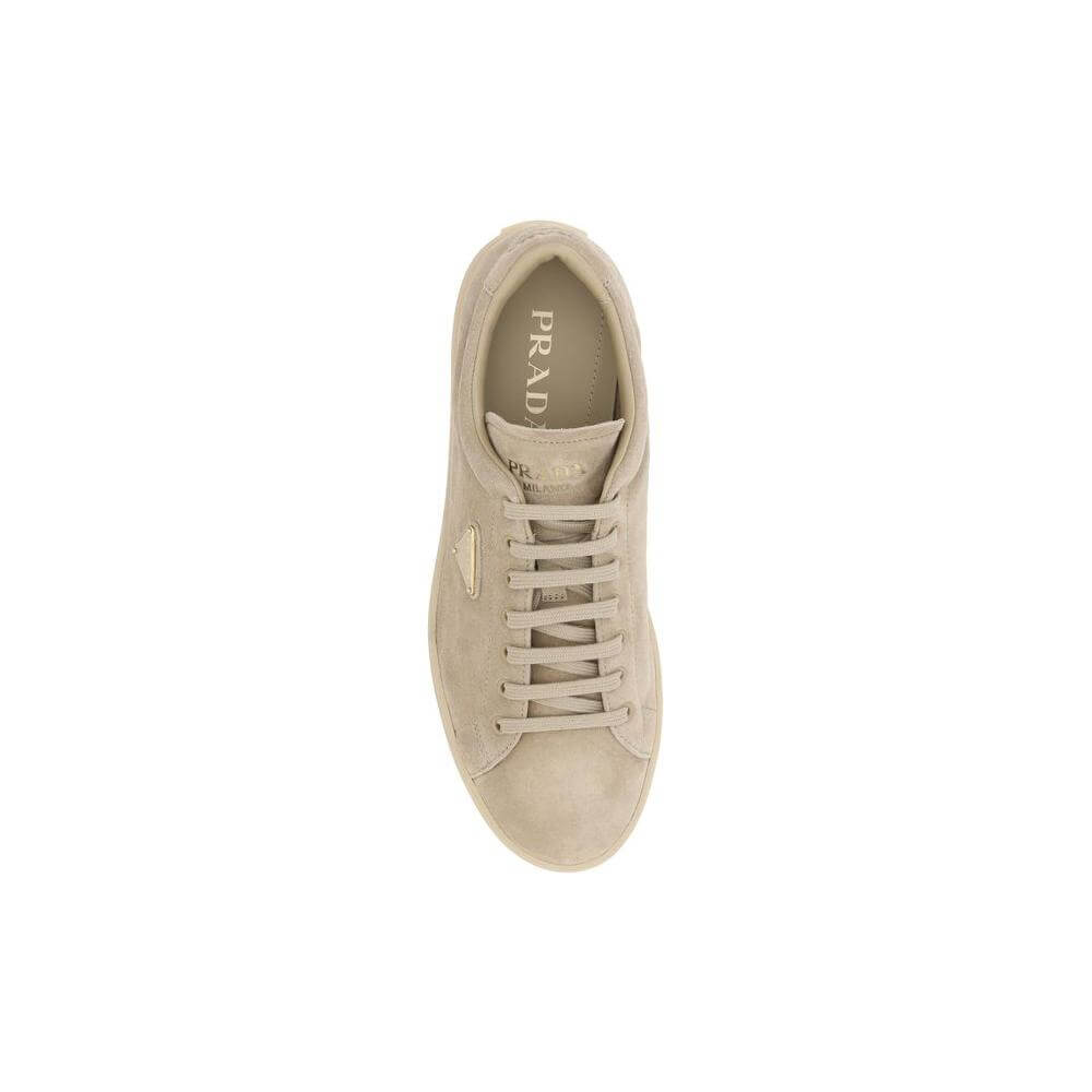 Top view of beige Prada suede sneaker with round toe, front laces, logoed insole, and iconic triangular plaque on the side panel.