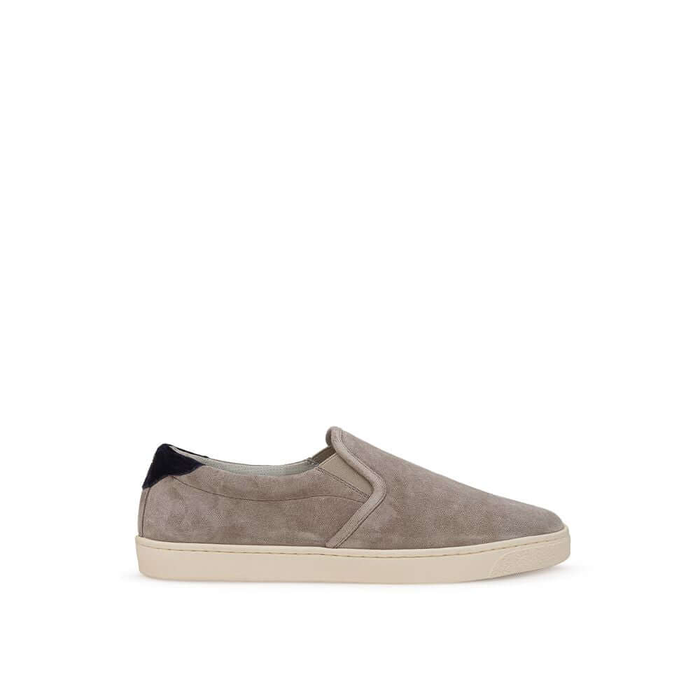 Brunello Cucinelli gray suede slip-on sneaker with white rubber sole and black back detail, featuring 'Solomei' print in gold.