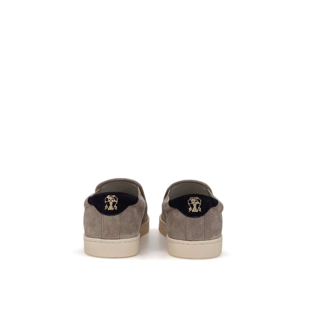 Rear view of Brunello Cucinelli gray leather slip-on sneakers with black and gold 'Solomei' print detail, white rubber sole.