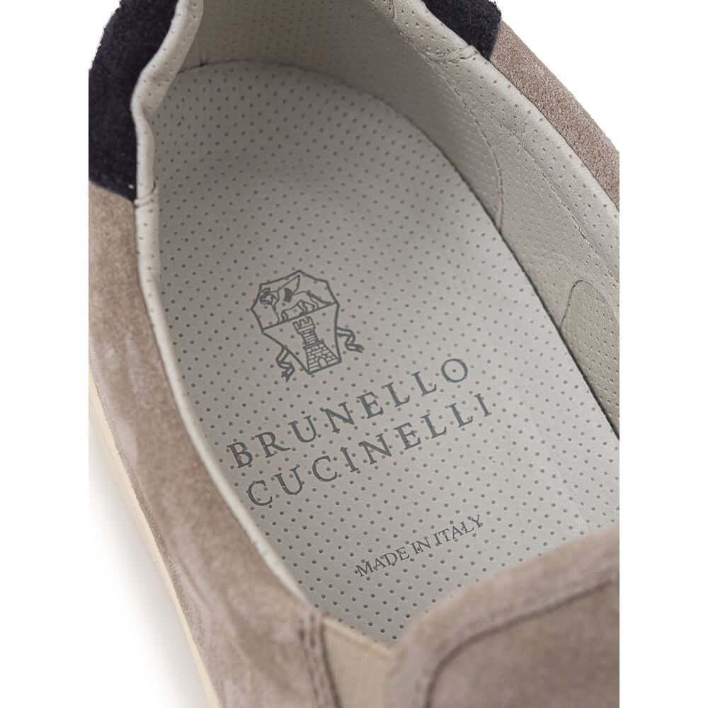 Brunello Cucinelli suede slip-on sneaker showcasing logo and interior detail, made in Italy.