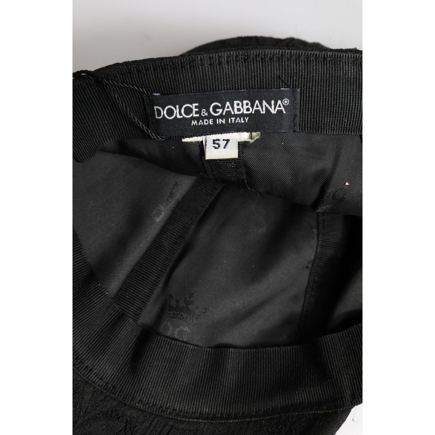 Inside view of a Dolce & Gabbana black floral jacquard baseball cap showing the label and size 57 tag.