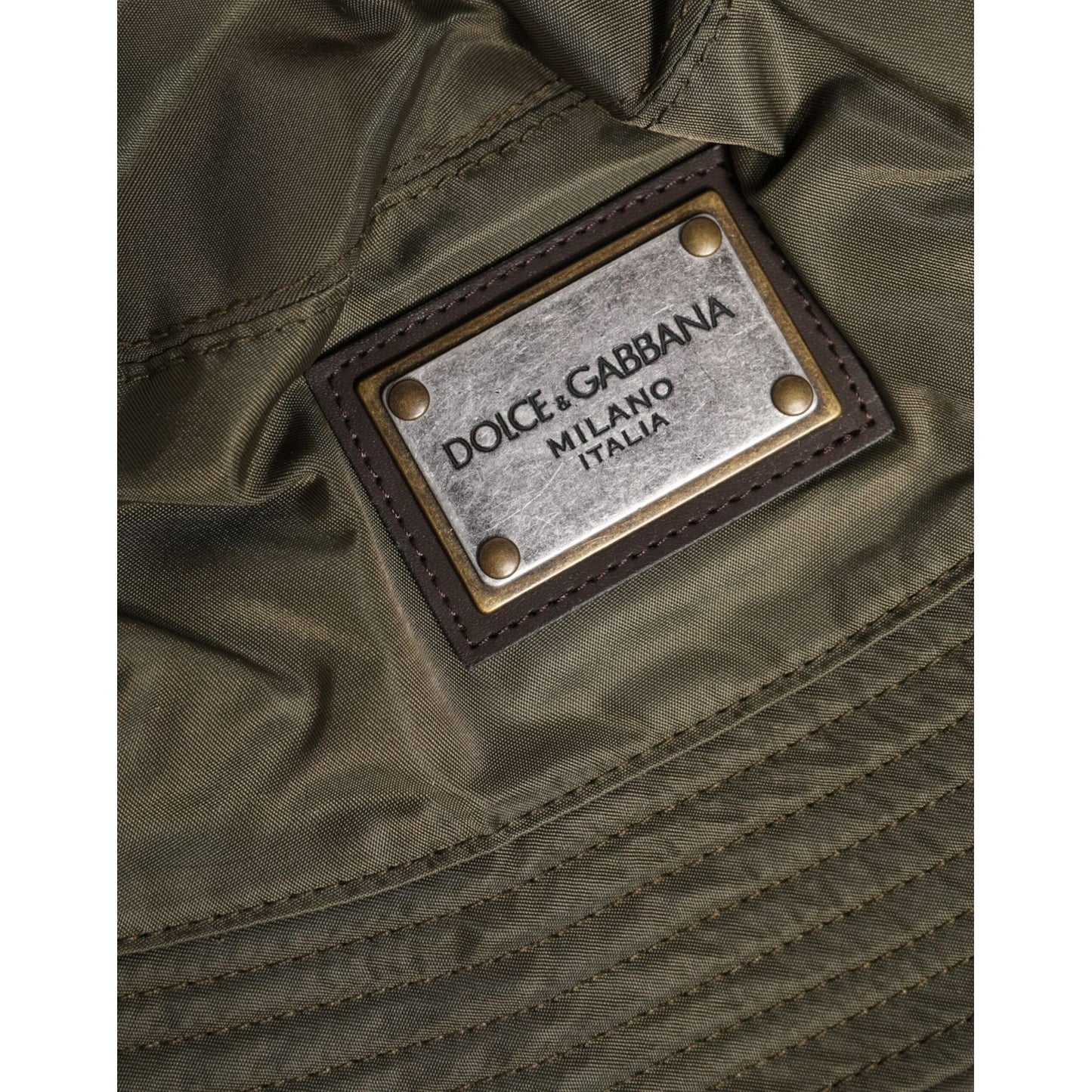 Dolce & Gabbana brown bucket hat with DG plaque, made in Italy, close-up of logo detail. Men’s polyester cap with viscose lining.