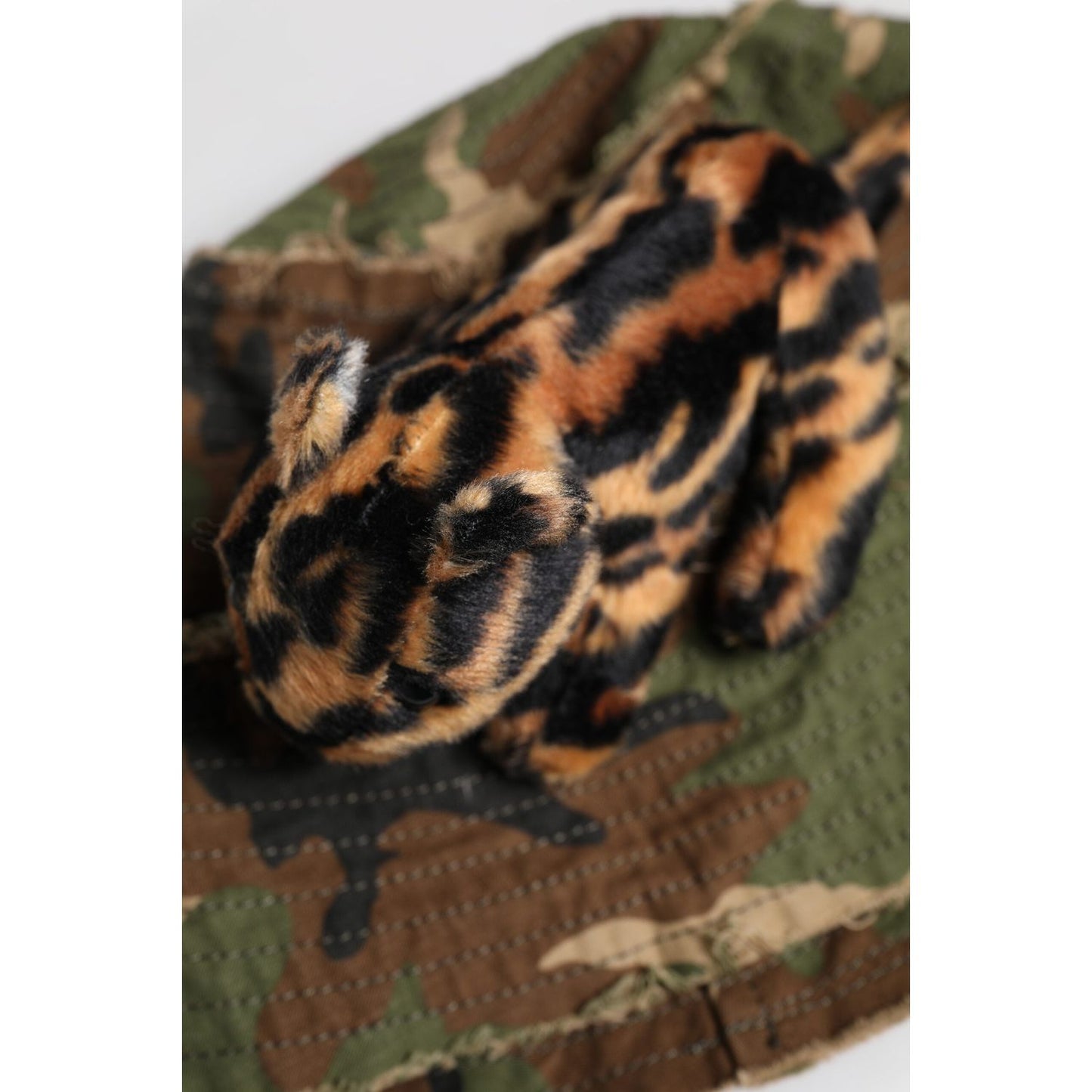 Leopard-pattern plush toy resting on a camouflage fabric background, showcasing rich textures and natural earth tones. Perfect for decor.