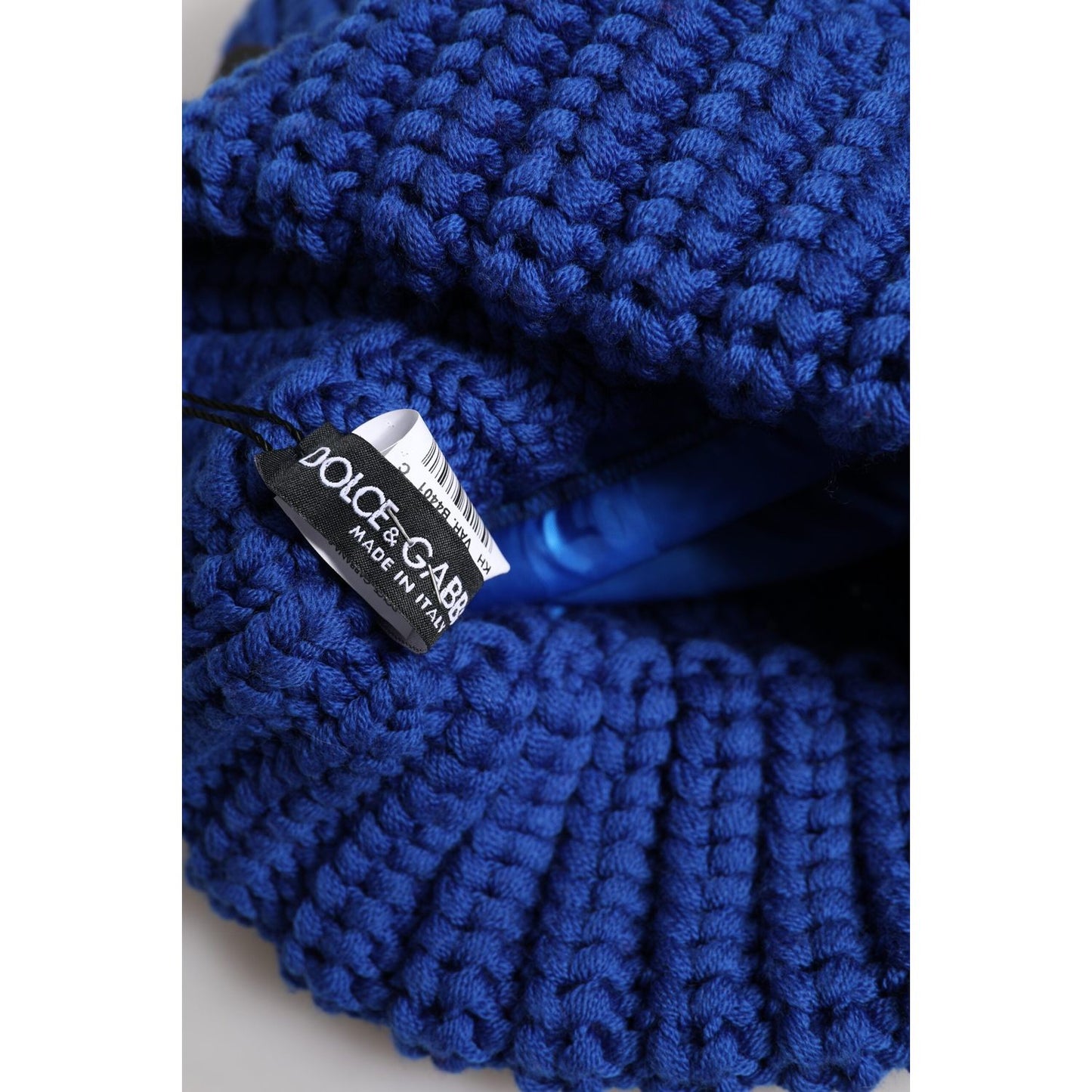 Dolce & Gabbana blue wool knitted beanie hat with logo tag visible, made in Italy, 100% virgin wool, close-up view.