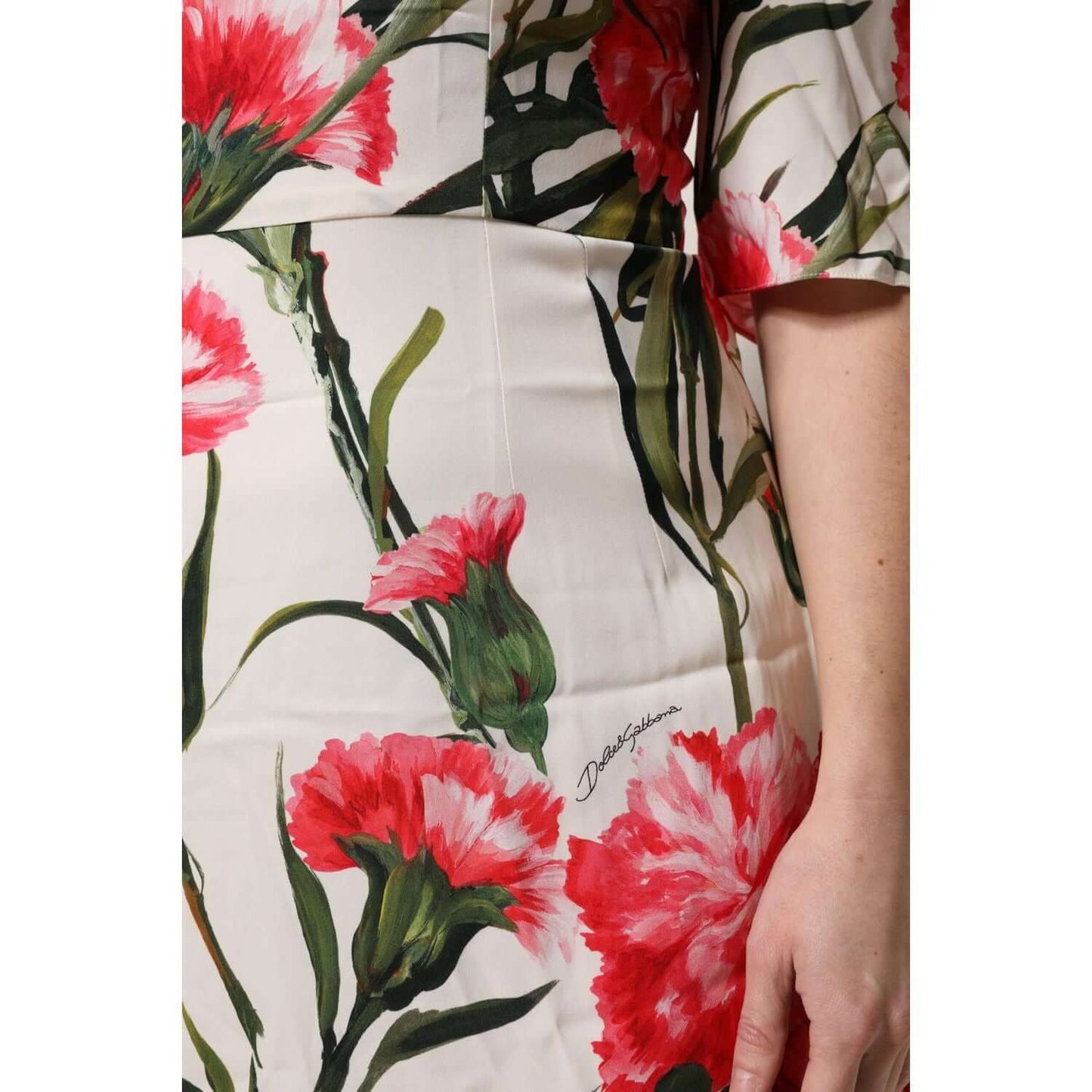 Close-up of Dolce & Gabbana pink floral print sheath dress, showcasing silk fabric and green stems, highlighting logo detail.