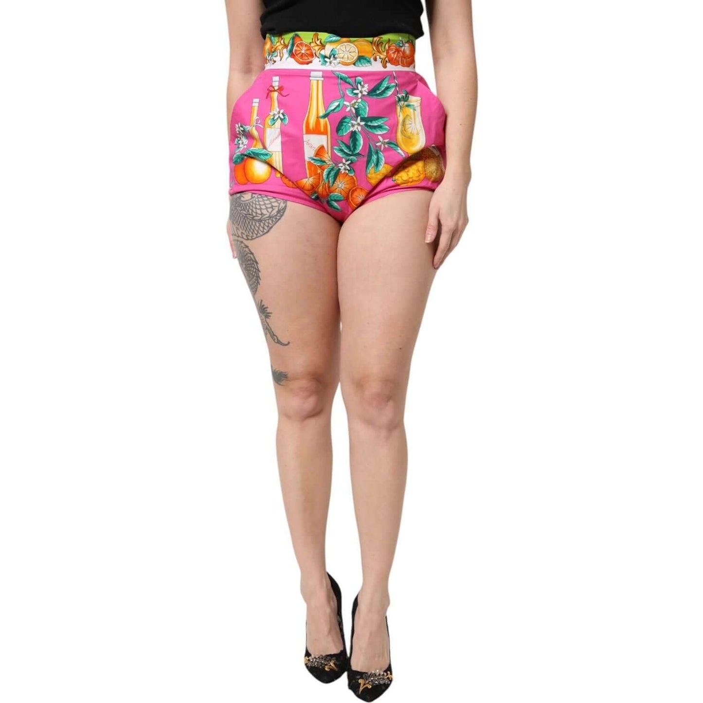 Model wearing Dolce & Gabbana pink high waist hot pants shorts with vibrant fruit print, 100% cotton, made in Italy.