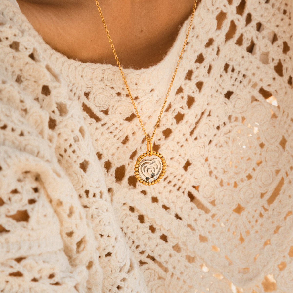 Close-up of AN JEWELS JEWELRY Mod. AL.NSOKSSYC necklace with a heart-shaped pendant, worn on a white lace top.