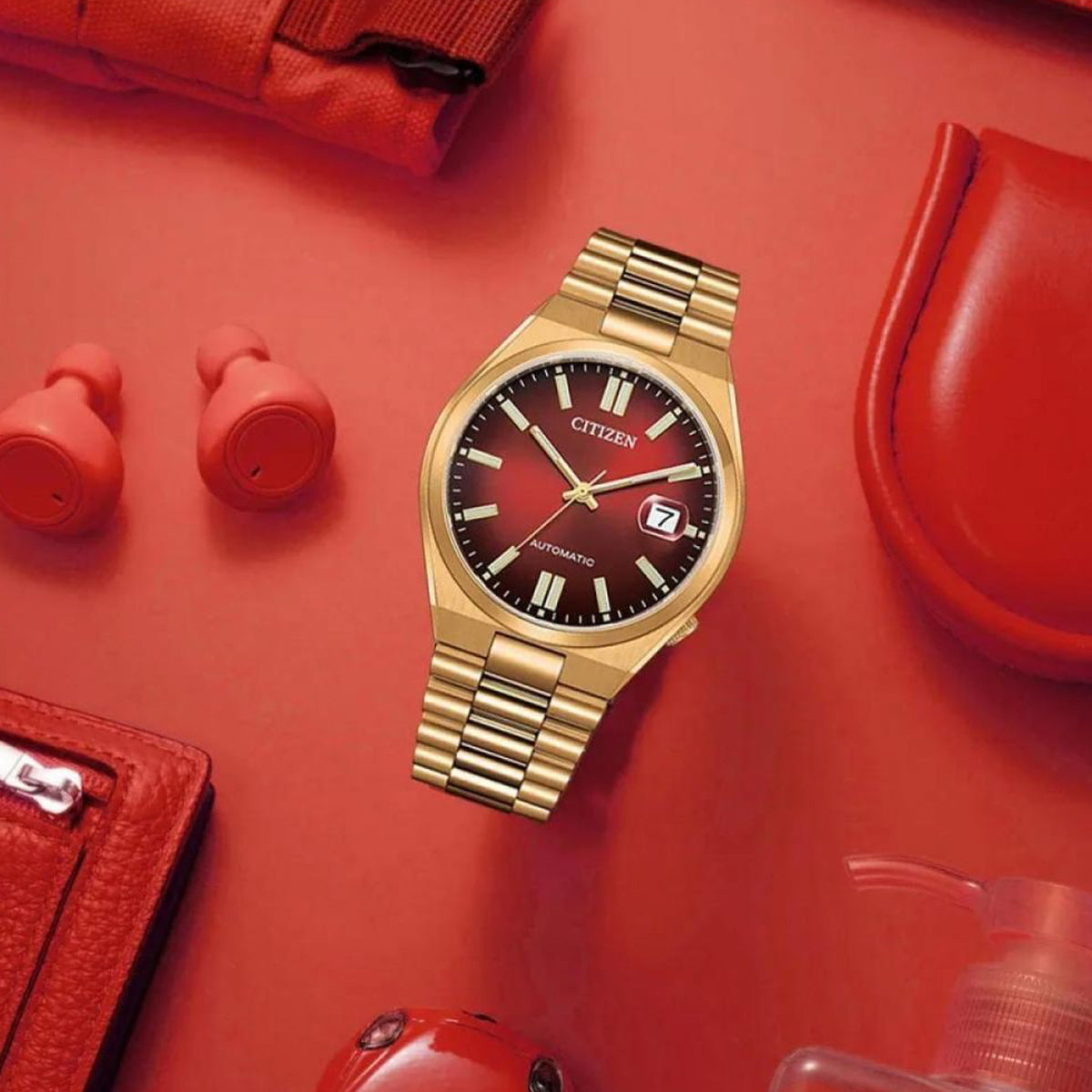 CITIZEN Mod. TSUYOSA Automatic - RED wristwatch with gold IP stainless steel case and strap, 5 ATM water resistance, displayed with red accessories.