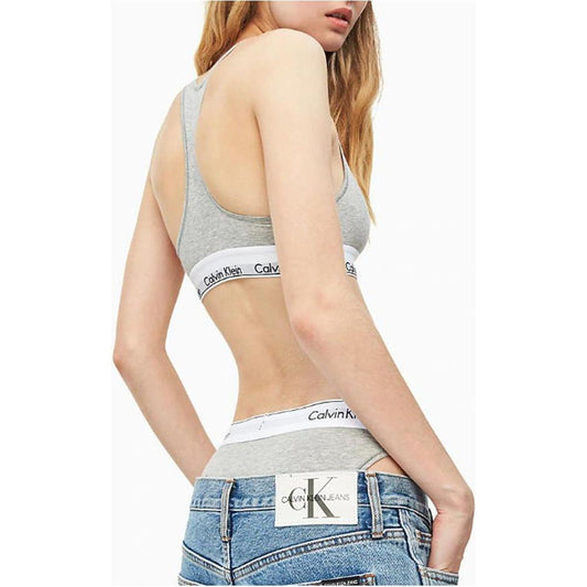 Woman wearing Calvin Klein gray cotton underwear with a minimalistic design and logo waistband, paired with jeans, side view.