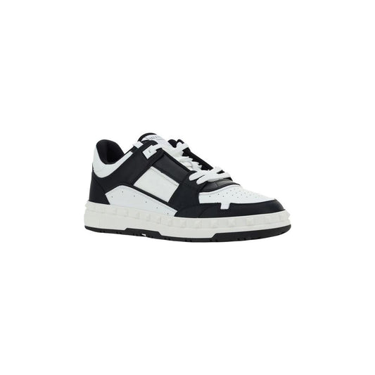 Valentino Garavani leather sneakers with laces, flat sole, conical heel studs, and embroidered logo on front tab.