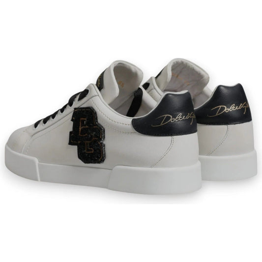 Dolce & Gabbana white leather low top sneakers with DG logo, black accents, and lace-up closure. Lightly preowned with minor wear.