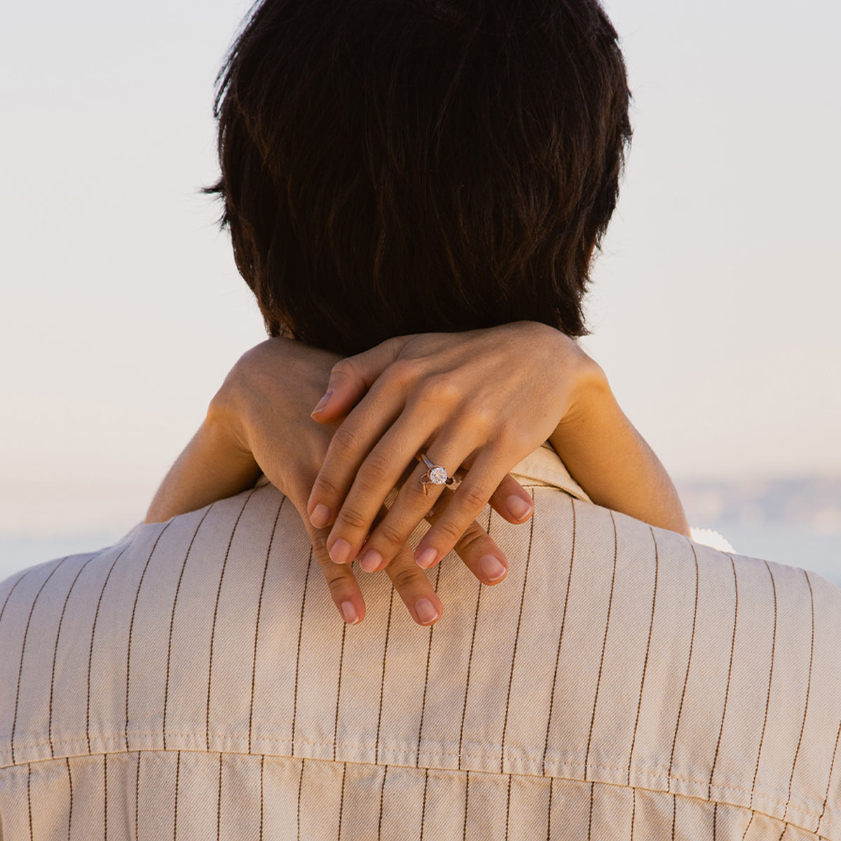 Close-up of a woman embracing a person, showing a ring on her finger.