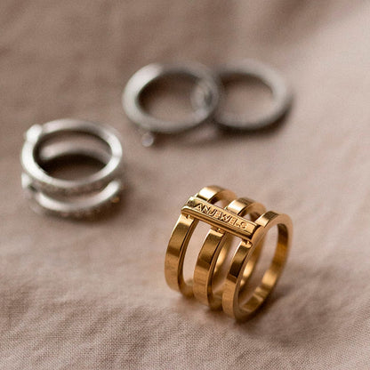 AN JEWELS JEWELRY Mod. AR.R3NS02Y-8 gold ring on beige fabric with silver rings in background