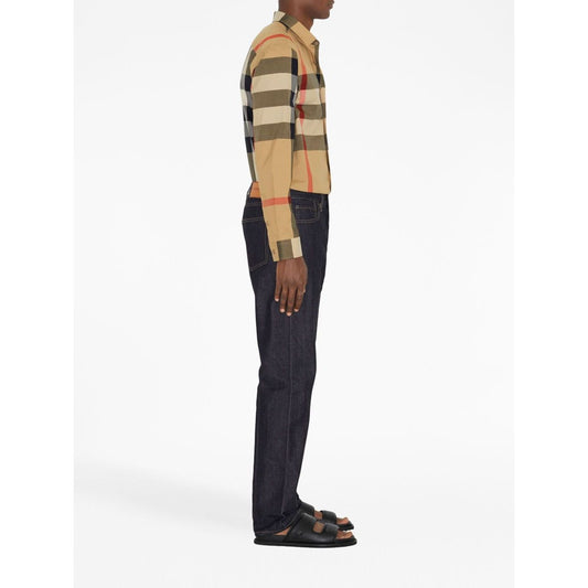 Side view of model wearing Burberry Check cotton shirt with classic collar and curved hem, paired with dark jeans and sandals.
