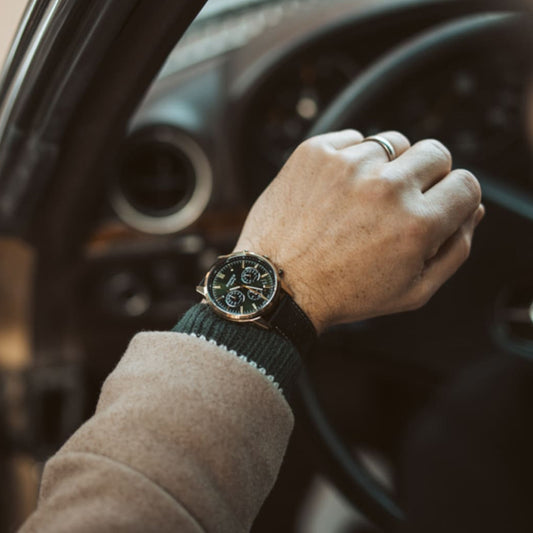 CASIO EDIFICE Mod. STANDARD CHRONOGRAPH GOLD - GREEN wristwatch worn by a person in a car, featuring a leather strap and quartz movement.