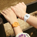 Two people wearing watches; right wrist features CASIO VINTAGE Mod. F-91 BIO RESIN STRAP - WHITE, left wrist shows an orange watch.