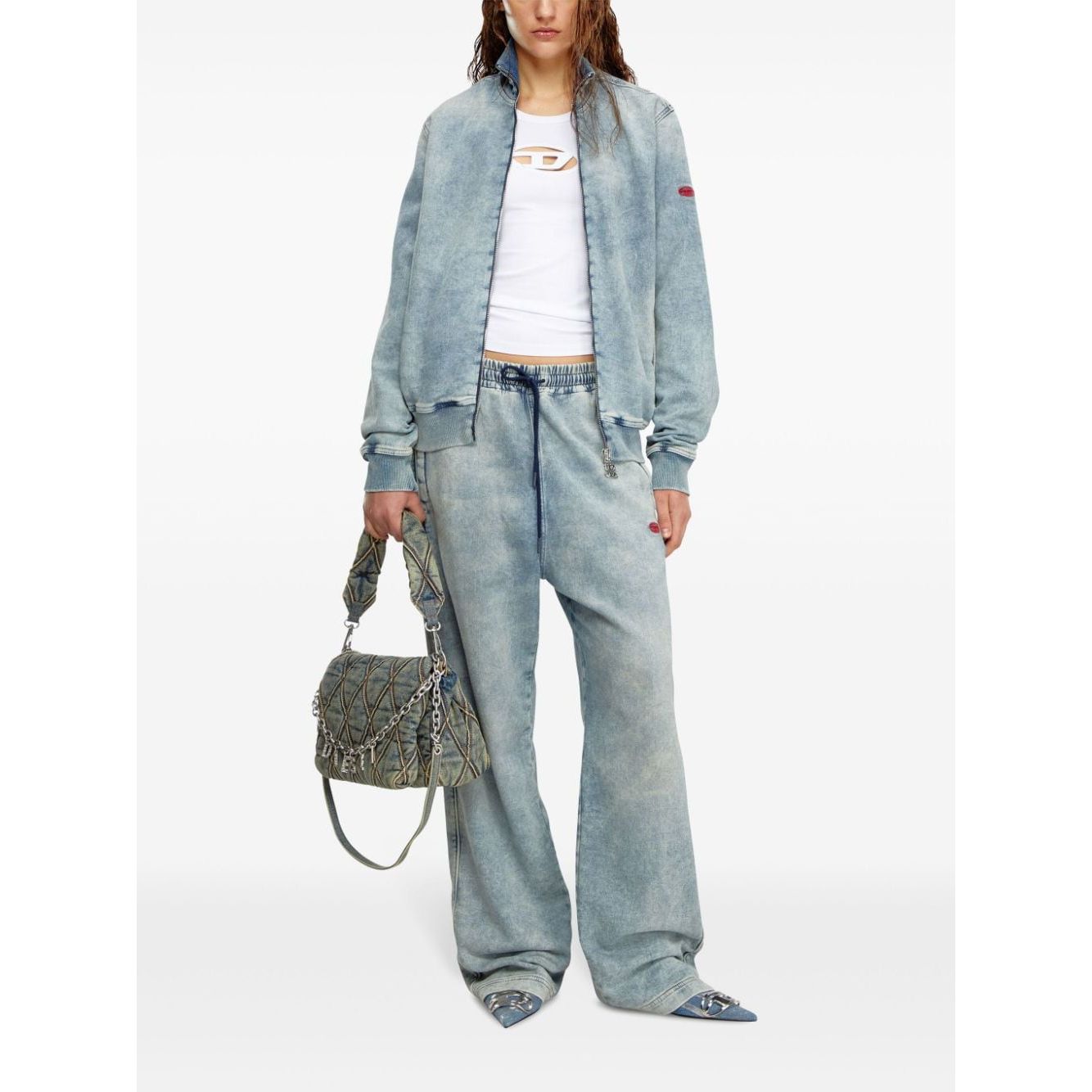 Model wearing Diesel Top White and denim jacket with matching pants, holding a designer handbag, showcasing casual fashion style.