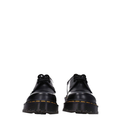 Alt Tag: Dr. Martens Black Leather Oxfords And Derbies with rubber soles and lace-up design, front view displaying casual style footwear.
