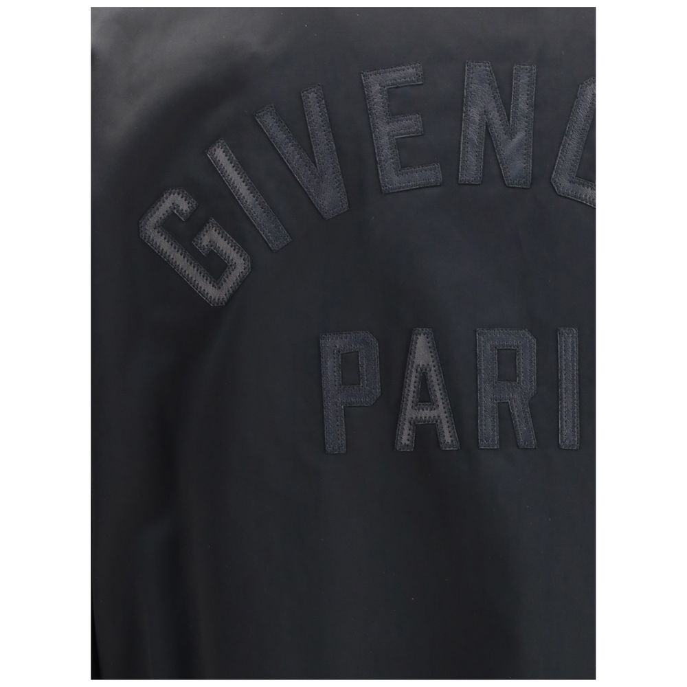 Close-up of Givenchy Black Cotton Bomber featuring leather GIVENCHY Paris logo appliqué on satin material.