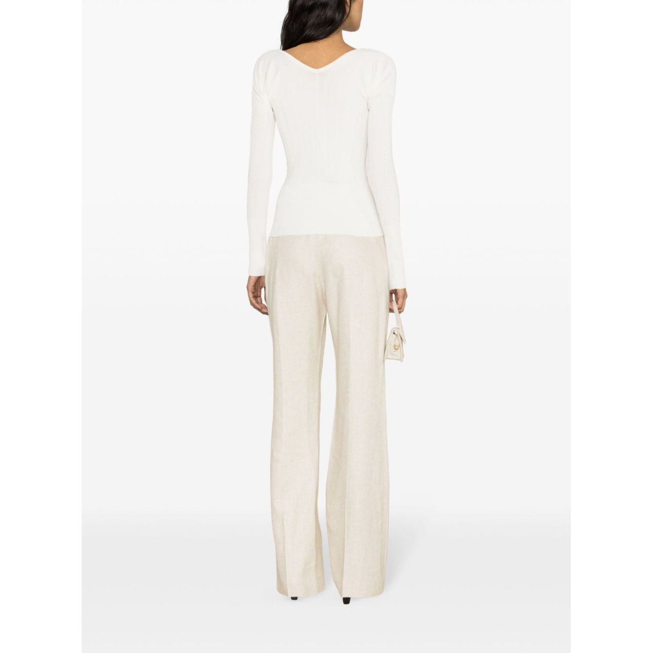 Back view of model wearing JACQUEMUS Top White with long sleeves and scallop edge, paired with neutral pants, showcasing V-neck and ribbed design.