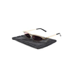 The Attico Norma sunglasses with gold-tone UV-protective lenses, logo-engraved arm, and curved tips on a black case.