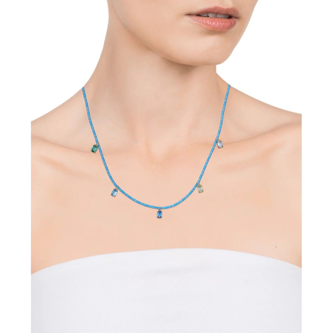 Woman wearing a delicate blue necklace with gemstone pendants.