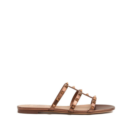 Valentino Garavani Rockstud Low Slide Sandal in Laminated Nappa Leather, brown flat sandals with signature Rockstud embellishment.