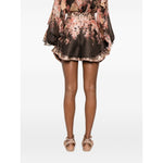 Rear view of Zimmermann Illuminate Flutter Shorts with floral print, ruffled trim, and concealed rear fastening, worn by a model.