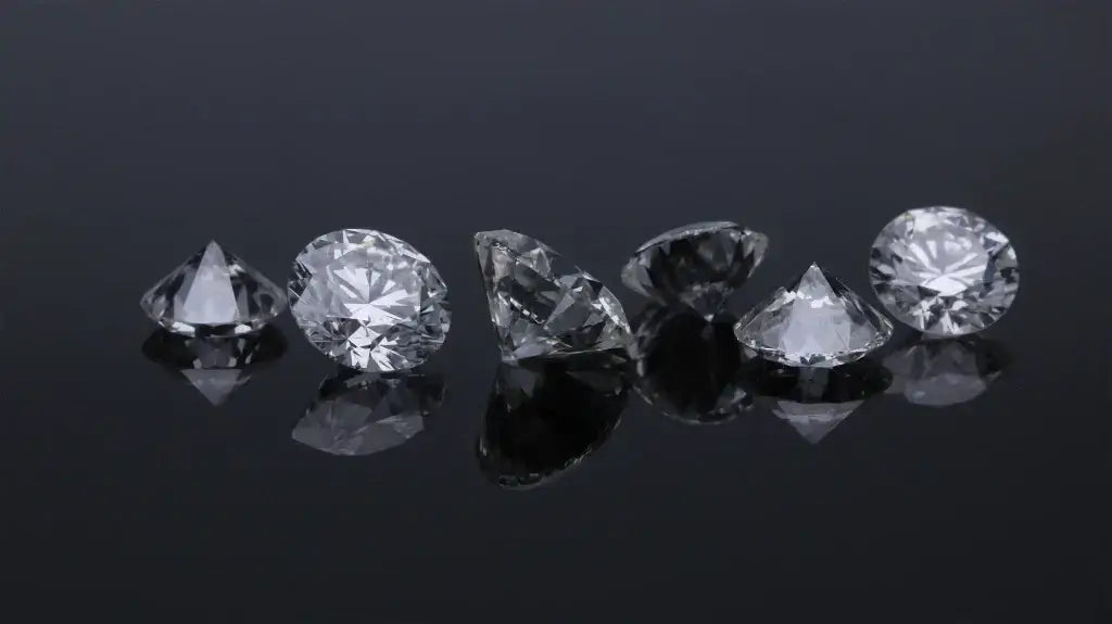 Loose round cut diamonds sparkling on a glossy black surface, showcasing brilliance and craftsmanship.