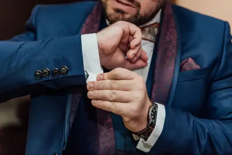 Close-up of a man adjusting cufflinks on a formal blue suit, showcasing luxury fashion and style.